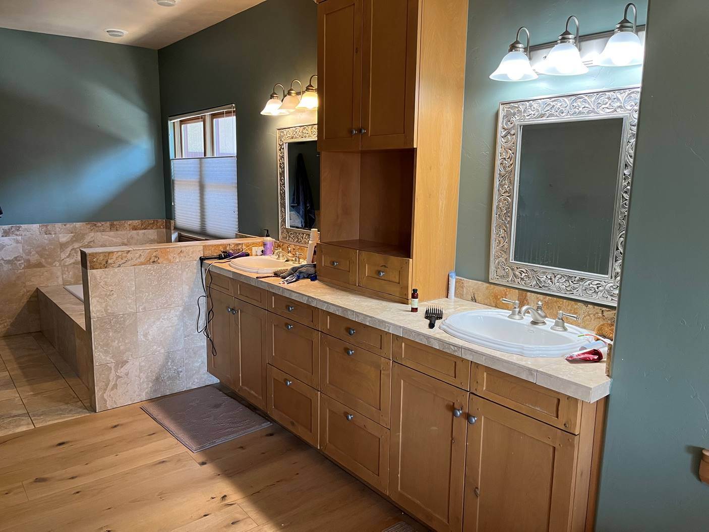 Master bathroom before painting, with honey oak vanity cabinets and dark green walls