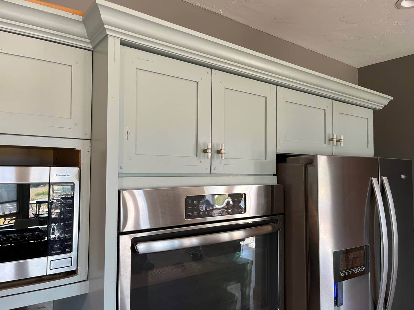 Close up of painted cabinet crown molding showing a clean sprayed finish and sharp cut line against the wall