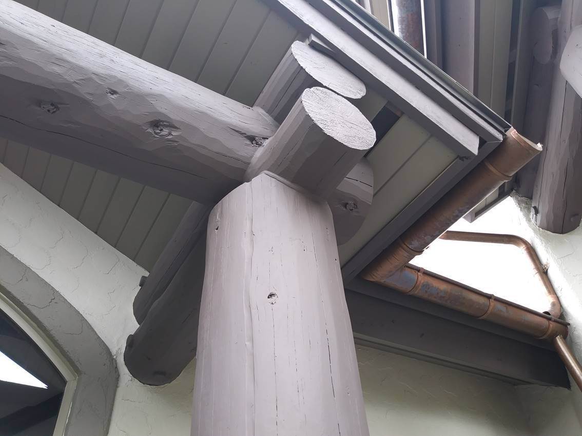 Timber beam and column joint painted a soft grey with a clean cut line where it meets the soffit and stucco