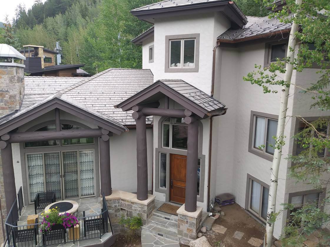 Completed exterior painting on a stucco home with repainted timber columns, trim and entry surround