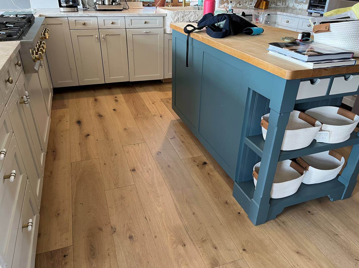 Finished kitchen after cabinet painting in a Naples style home, with a deep navy island, painted cabinets and wood floors