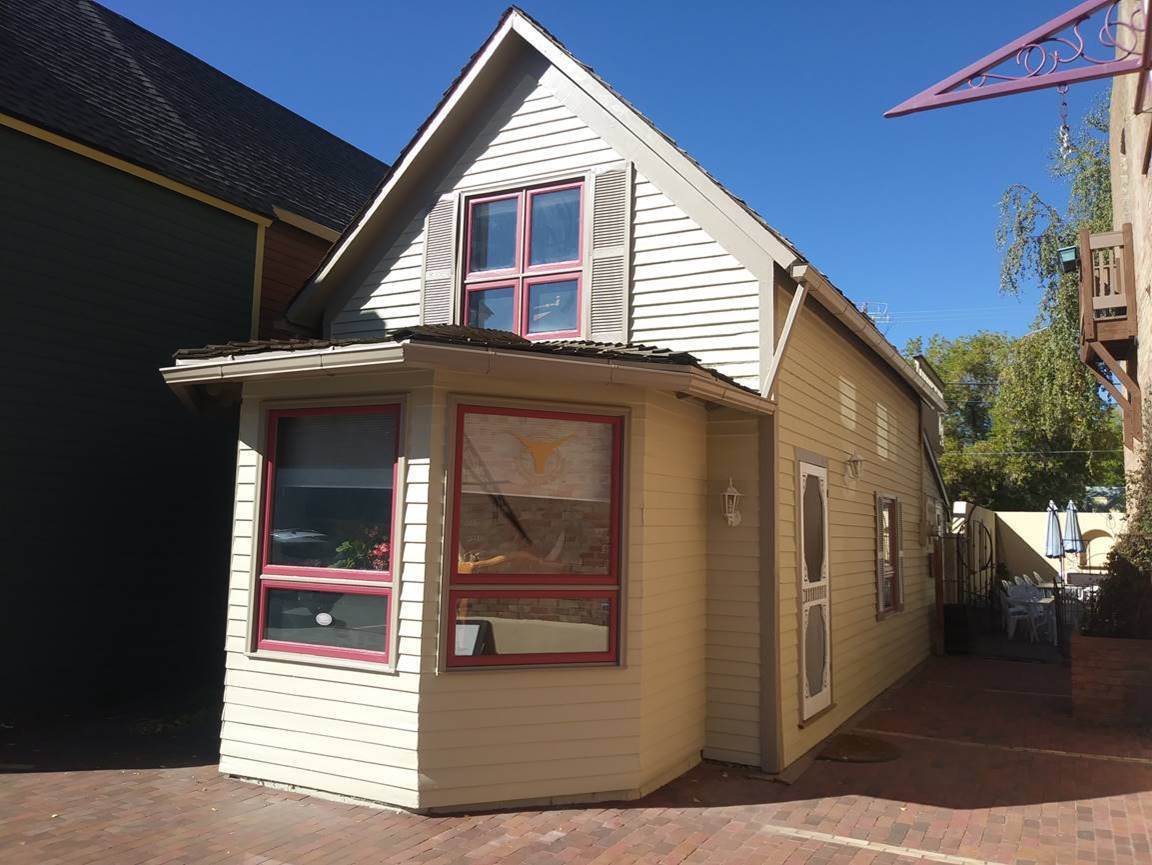 Historic wood clapboard cottage after a full exterior repaint with cream siding and deep red window sashes