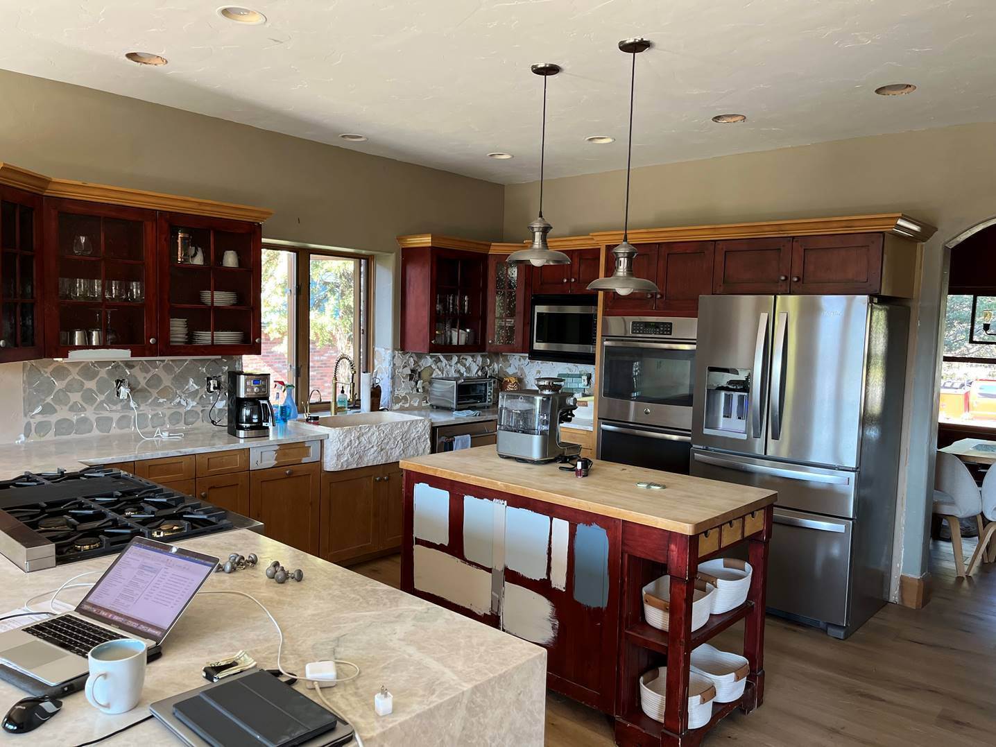 Kitchen before painting, with dated cherry stained cabinets, a red island and tan walls