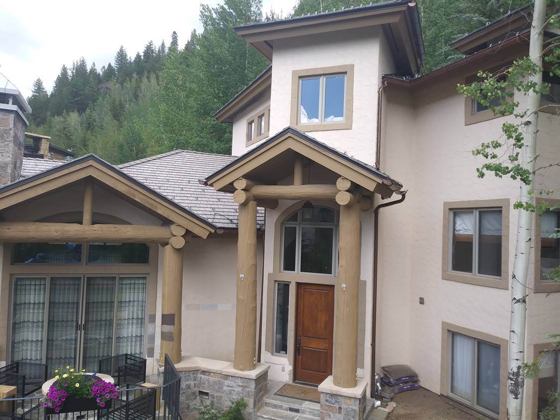 Repainted stucco and timber home exterior with fresh trim, an exterior painting project by Sun Up Painting
